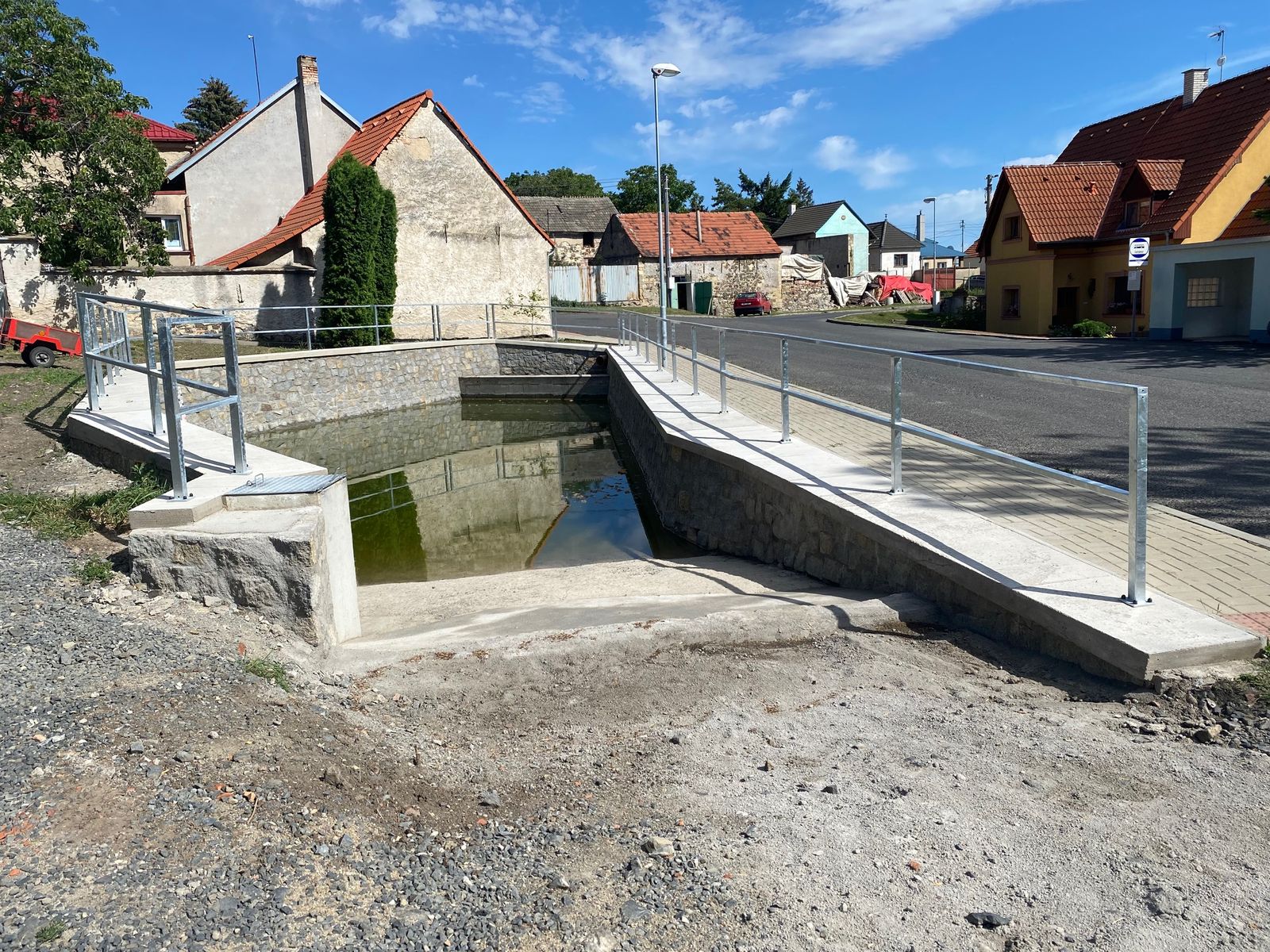 Dokončená požární nádrž se zábradlím a chodníkem v Chraberci